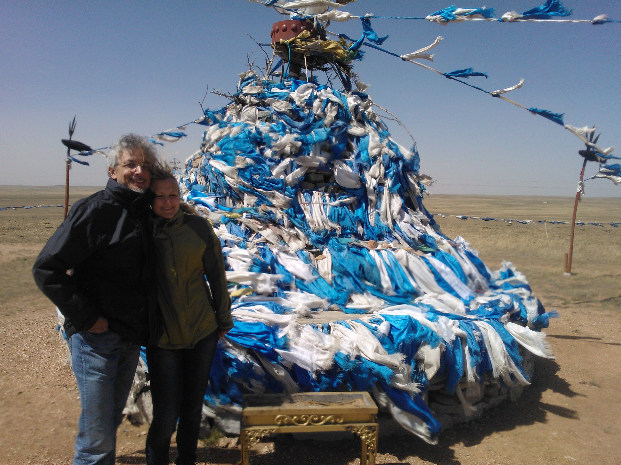 Traveler beside a mound decorated with blue ceremonial ribbons on the plains