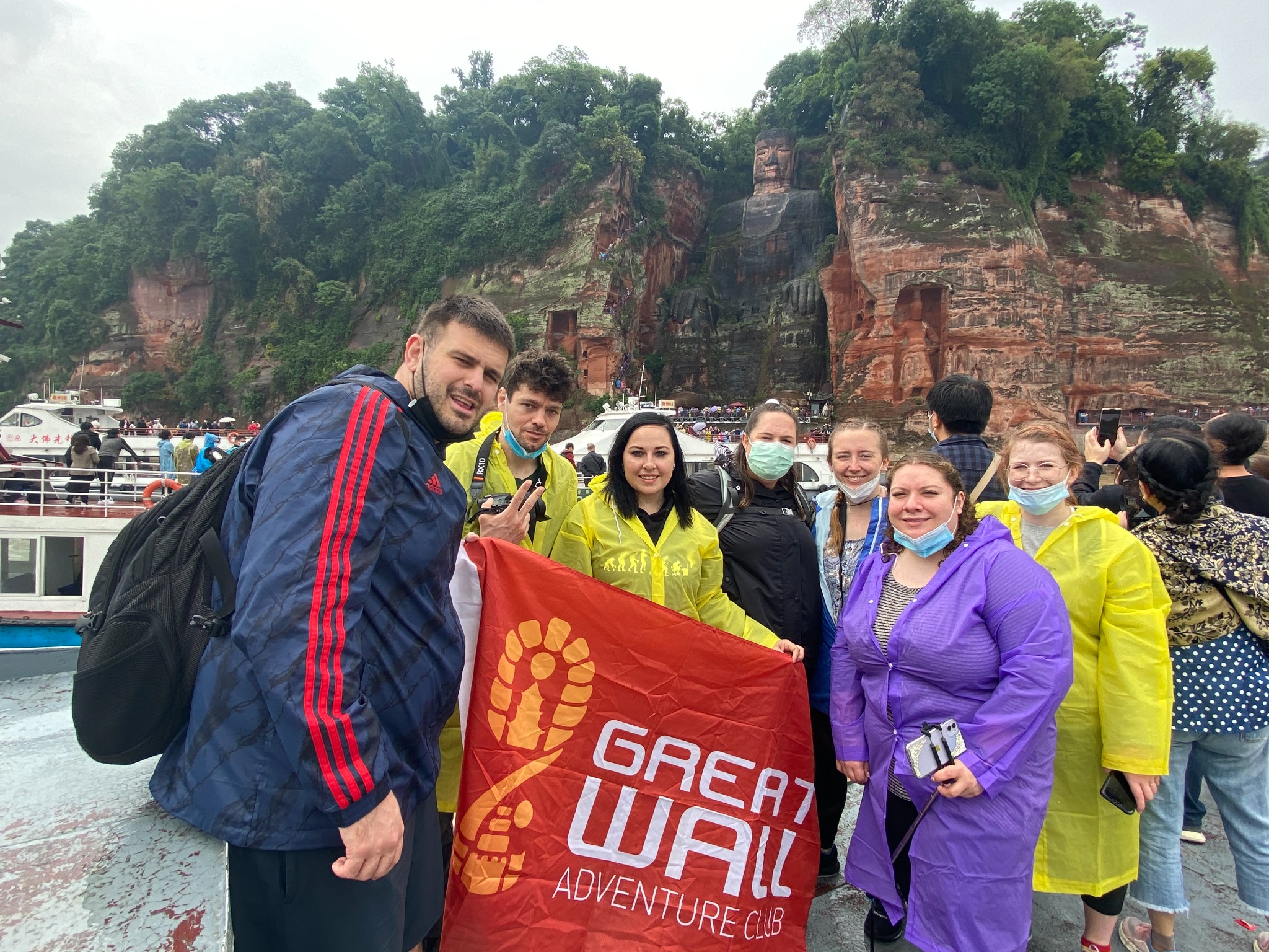 Traveler group holding a Great Wall Adventure Club banner near red cliffs